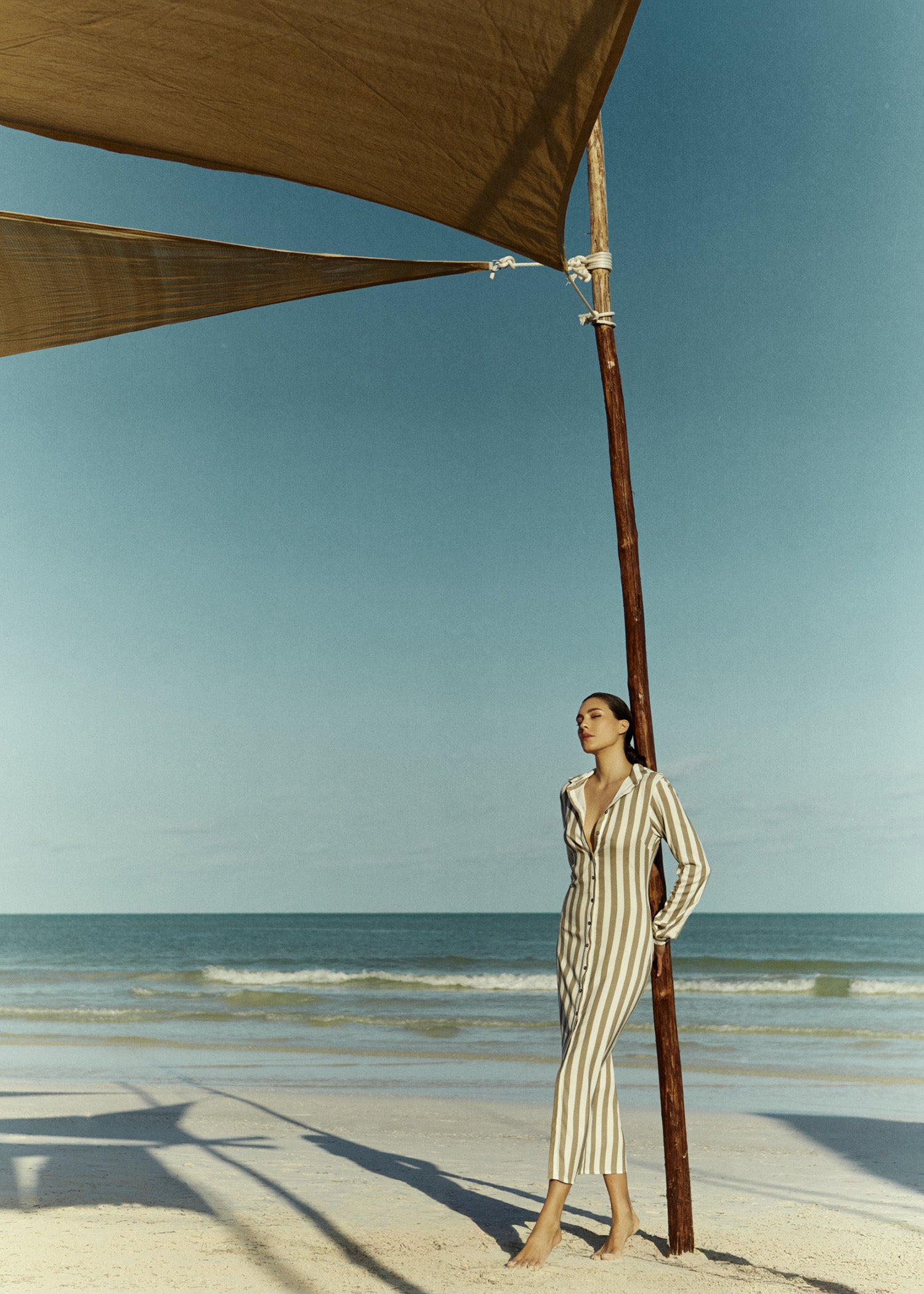 Model wearing the Collared Button-Down Maxi Shirt Dress Natural Stripe in Striped Stretch Twill, moves easily from poolside to aperitivo.