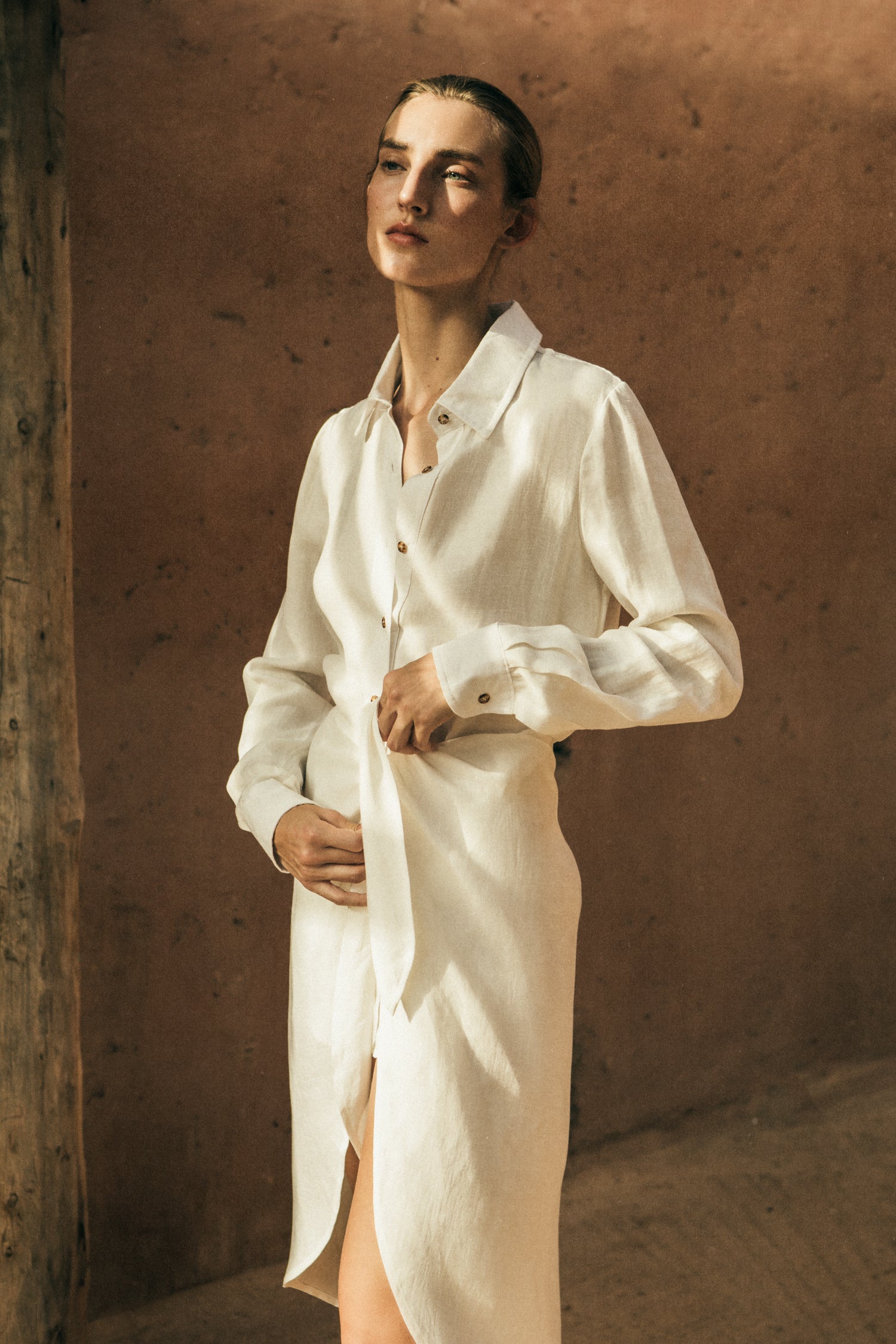 Model wearing the L.A. Button Down Asymmetric Wrap Midi Dress in Cupro Linen Blend, combining the structure of a button-down with the ease of a wrap silhouette.