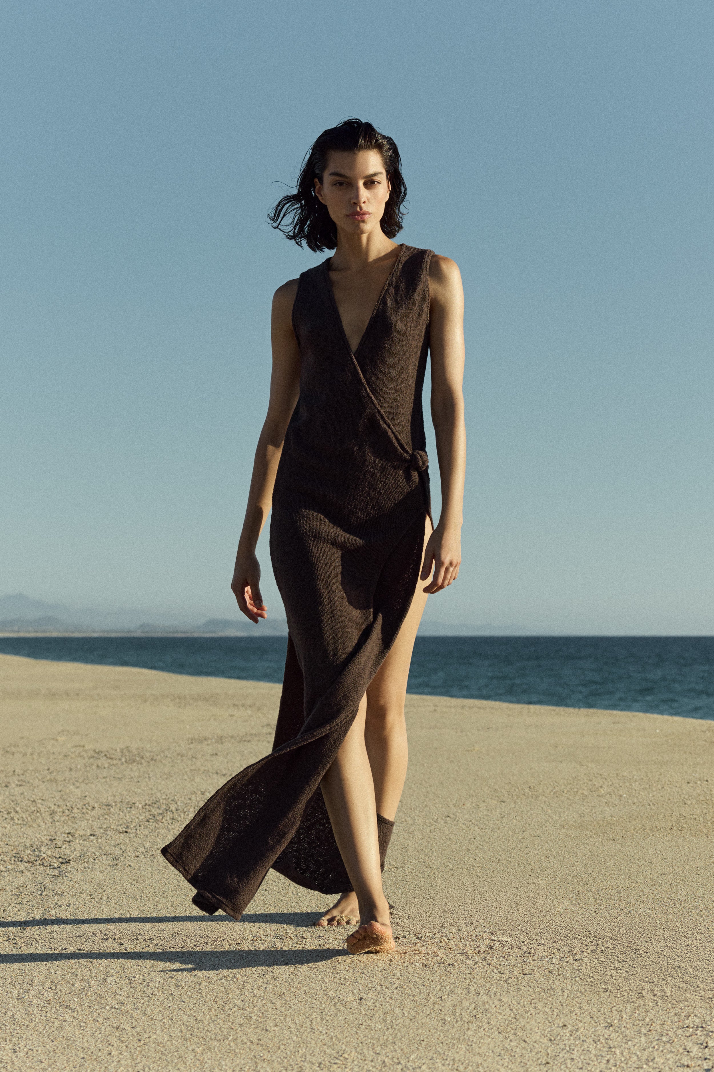 Model wearing Plunging Knot Wrap Dress in crochet cotton knit with a plunging neckline, knot detail, and draped wrap silhouette in a breathable, lightweight knit.