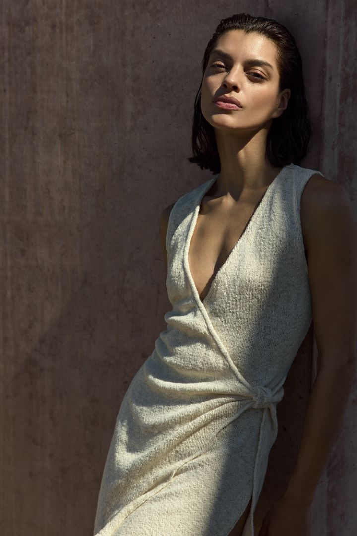 Model wearing Plunging Knot Wrap Dress in crochet cotton knit with a plunging neckline, knot detail, and draped wrap silhouette in a breathable, lightweight knit.