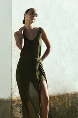 Model wearing the D.K. Midi Wrap Dress in Cypress Green, featuring a classic scoop neck line and self-tie wrap skirt against a white wall
