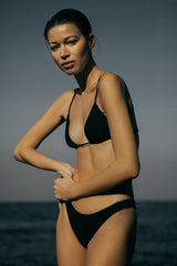 Model wearing Eighties High-Cut Black Bikini Bottom designed with a figure-flattering high-cut leg in a range of seasonal and classic shades.
