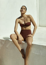 Model wearing the High-Waist Bikini Bottom, an Anemos signature, combines retro charm with modern appeal through a high-rise waist and cheeky, flattering cut.