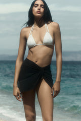 Model wearing the Knot Draped Mini Skirt in Luxe Cupro Jersey, the relaxed drape of the side knot elevates this summer piece making it right for the beach or thrown into your bag for a last minute getaway. 