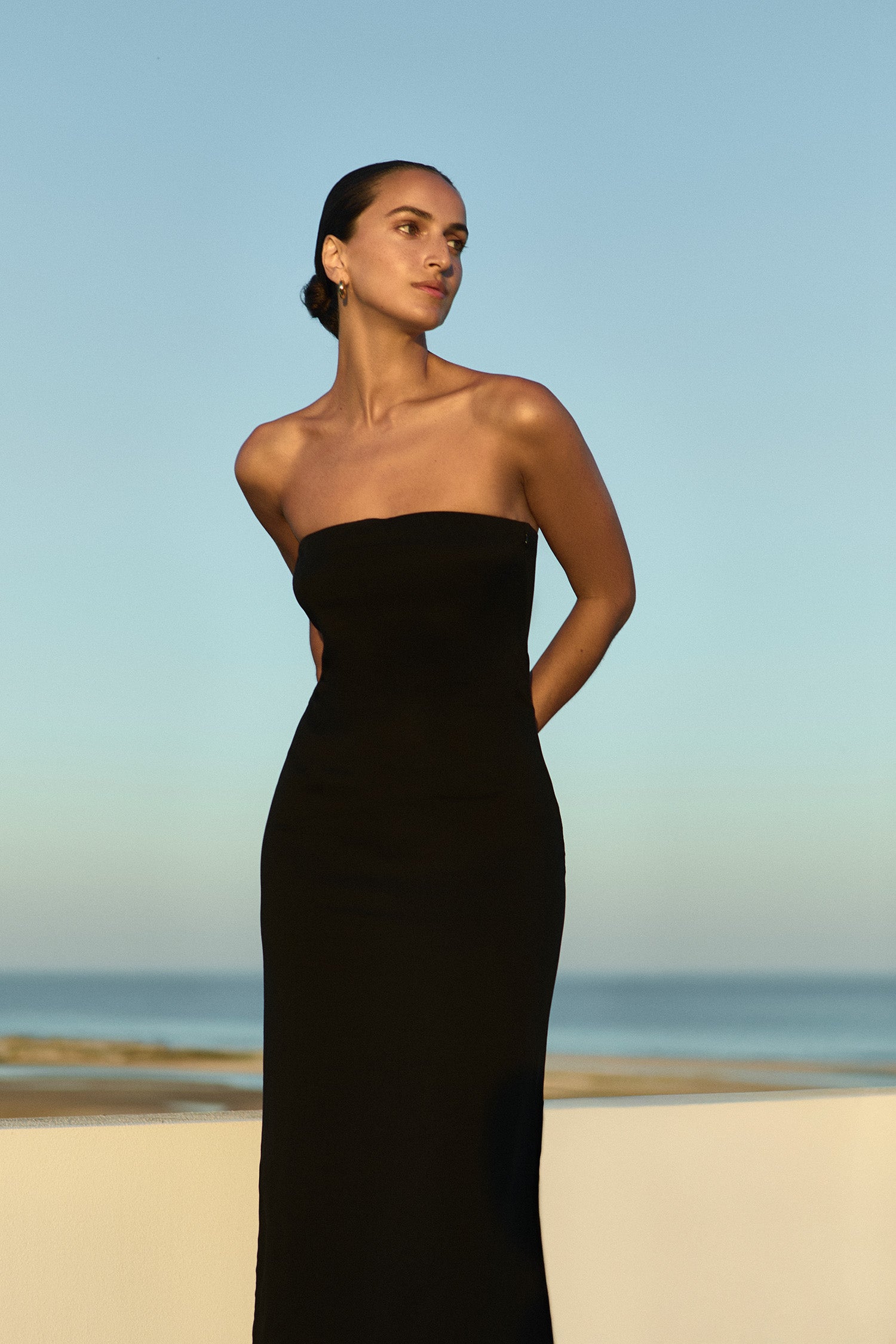 Model wearing the Strapless Midi Dress Black in Stretch Twill embodying minimalist elegance.