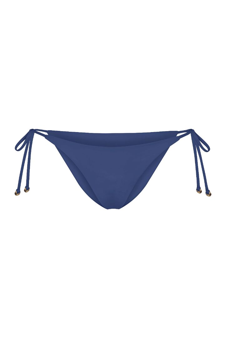 String Tie Bikini Bottom on a white background, featuring adjustable side ties with petite tortoise rings and a versatile high- or low-waist fit for a sleek ’70s-inspired look. 