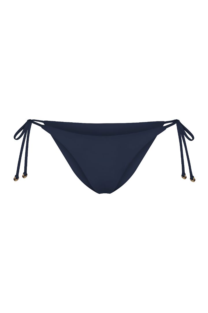 String Tie Bikini Bottom on a white background, featuring adjustable side ties with petite tortoise rings and a versatile high- or low-waist fit for a sleek ’70s-inspired look.