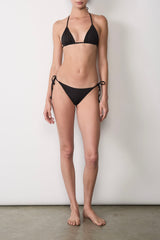 Ecomm Model wearing the String Tie Bikini Bottom, channeling ’70s-inspired simplicity with adjustable ties that can sit high or low on the waist, finished with petite tortoise rings for a polished touch.