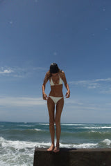 String Tie Bikini Bottom worn by a model, showcasing the adjustable side ties, low-waist fit, and tortoise ring details for a polished, retro-inspired swimwear style. 