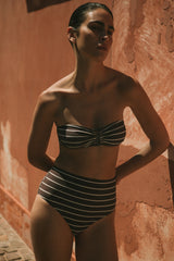 Model wearing the Tortoise Bandeau Bikini Top In Espresso Odd Stripes, featuring a classic bandeau silhouette with an elongated resin tortoise ring and a wider fit for added comfort and support.